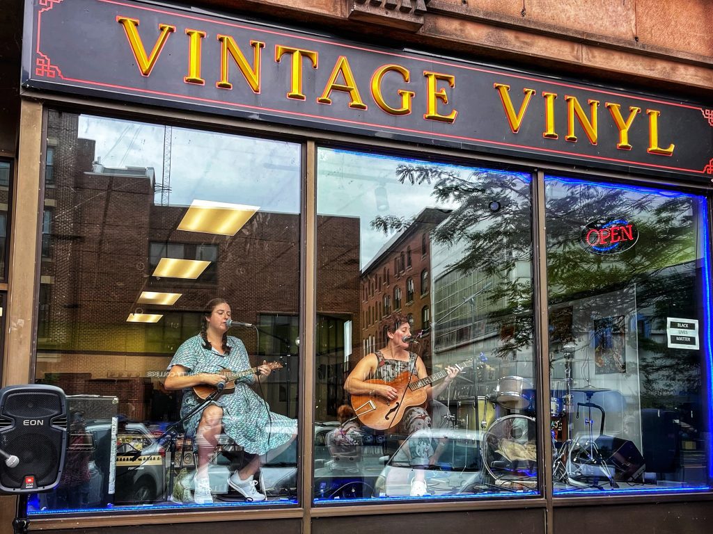 woman playing music in window of John Doe, Jr. Vintage Vinyl
